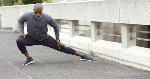 Senior african american man stretching side lunge for mobility and balance outdoors