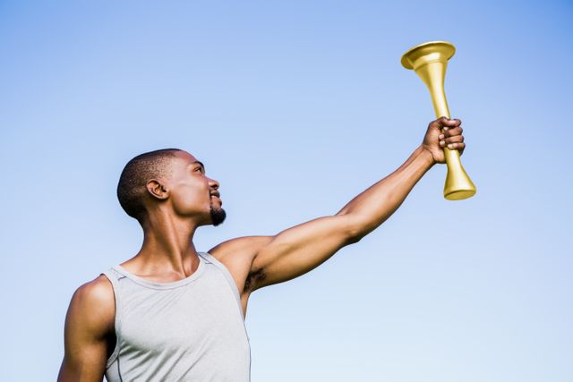 This image depicts an athlete holding a fire torch high in the air, celebrating victory in a stadium. Ideal for use in sports-related content, motivational materials, fitness promotions, and advertisements highlighting success and achievement.