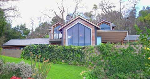 Modern hillside residence featuring triangular glass gable, balcony and ivy-clad wall