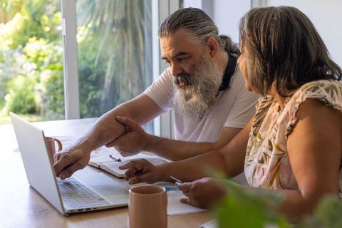 Senior couple reviewing finances on laptop at home for retirement planning and budgeting