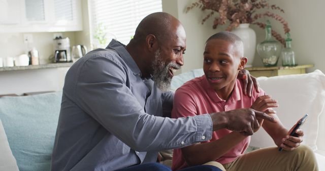 Father and Son Smiling and Using Smartphone Together in Living Room - Download Free Stock Images Pikwizard.com