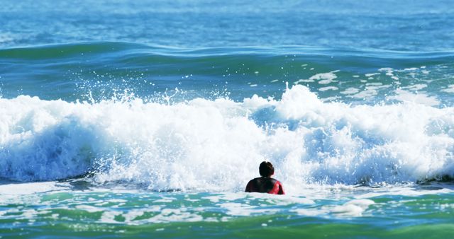 Person facing large waves while holding surfboard in ocean. Ideal for depicting surfing activities, water sports advertisements, ocean adventure themes, beach sports promotions, or summer leisure content.