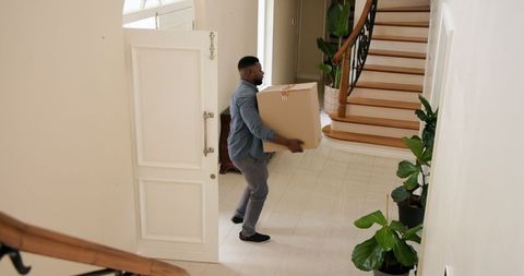 Man carrying cardboard box in elegant entrance hallway