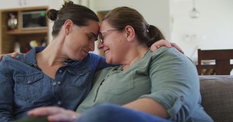 Loving Lesbian Couple Embracing On Sofa At Home