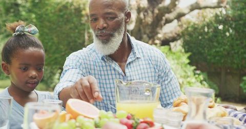 Family Enjoying Breakfast Outdoors with Grandfather and Granddaughter