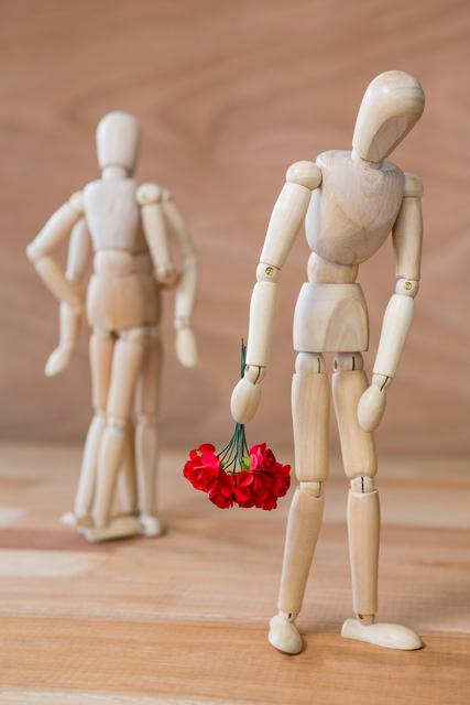 Conceptual image of figurine depressed with bunch of flowers walking away from couple