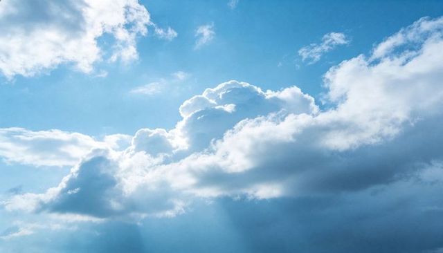 Backlit Cumulus Cloudscape with Sunrays Piercing Layered Blue Sky
