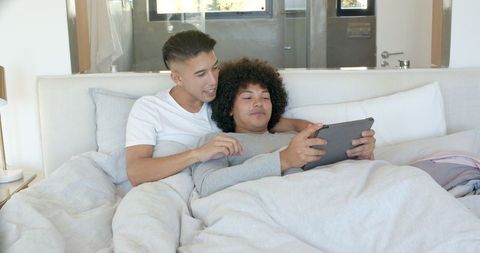 Couple Relaxing in Bed Sharing Tablet in Modern Bedroom