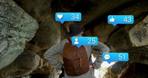 Adventurous hiker interacting with social media icons among rocks