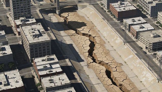 Aerial view of cracked city channel revealing massive fissure cutting through downtown