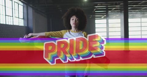 Empowered woman celebrating with rainbow pride flag indoors