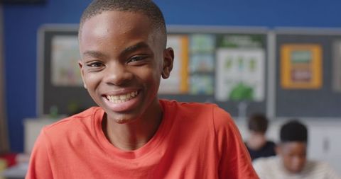 Smiling boy in classroom with engaged classmates