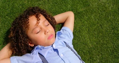 Child Relaxing on Grass with Eyes Closed Gently Sunbathing
