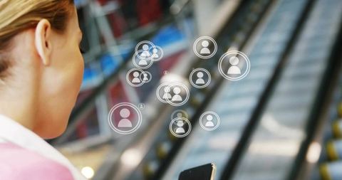 Woman using smartphone with digital connectivity icons at escalator
