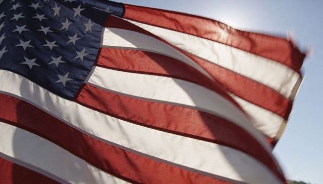 Backlit american flag waving in wind close-up stars and stripes patriotic banner holiday