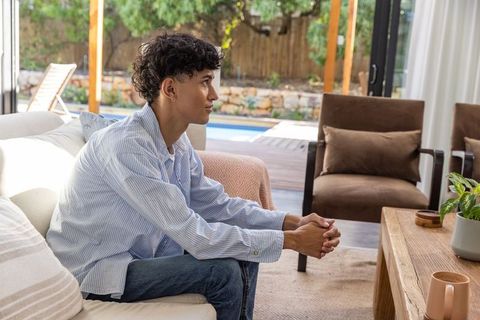 Man Relaxing on Sofa Looking Out Glass Door in Modern Living Room