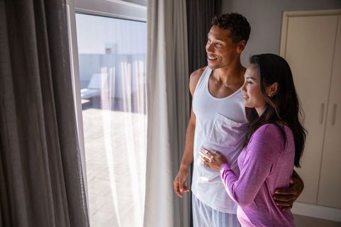 Diverse Couple Embracing by Sliding Glass Door, Serenity and Love