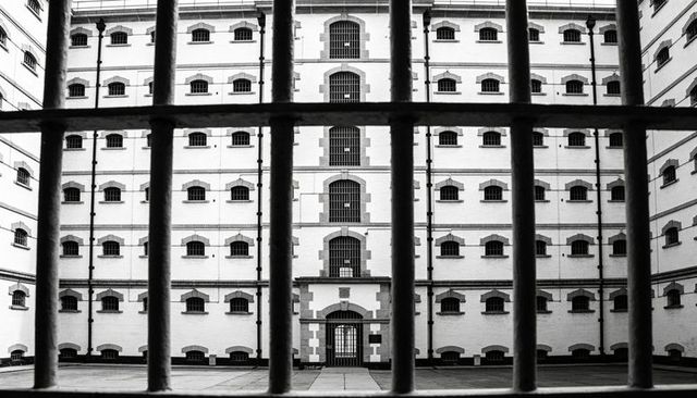 Framing victorian cellblock through iron bars monochrome courtyard symmetry