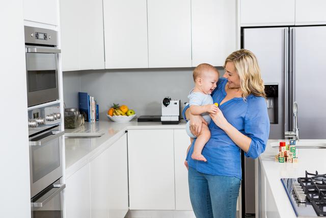 Mother holding her baby boy in kitchen at home
