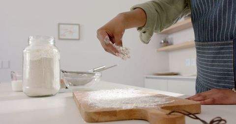 Hand Sprinkling Flour for Baking Preparation on Wooden Board
