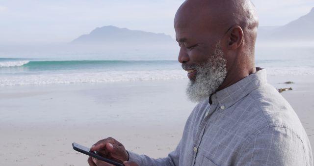 Senior Man Smiling at Beach Using Smartphone - Download Free Stock Images Pikwizard.com