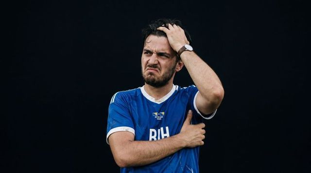 Frustrated male athlete holding head and clutching arm wearing blue bih jersey and watch