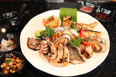 Assorted grilled seafood platter with sauces and garnishes