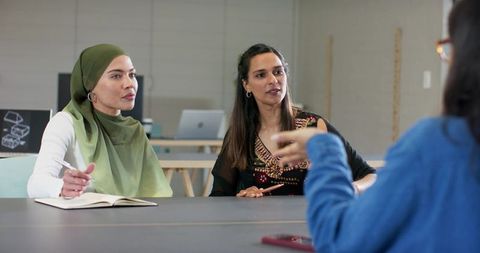 Multicultural female colleagues discussing project plans at minimalist modern office table
