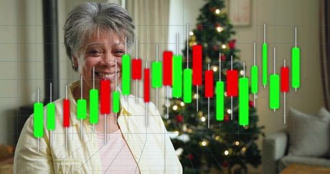 Smiling senior woman viewing candlestick trading chart with Christmas tree at home