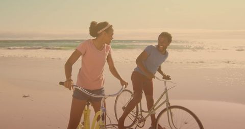Couple Enjoying Bike Ride Along Sunny Beach