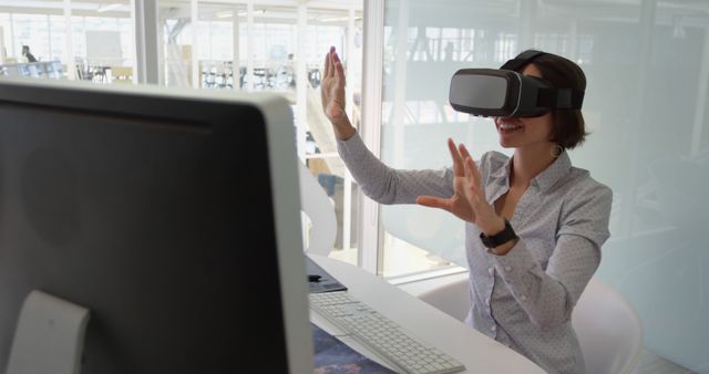 Woman technology enthusiast using virtual reality headset in office, demonstrating modern immersive experience. Ideal for showcasing innovation, digital transformation, and futuristic work environments. Suitable for articles on tech adoption in workplaces, virtual reality applications, and progressive work culture.