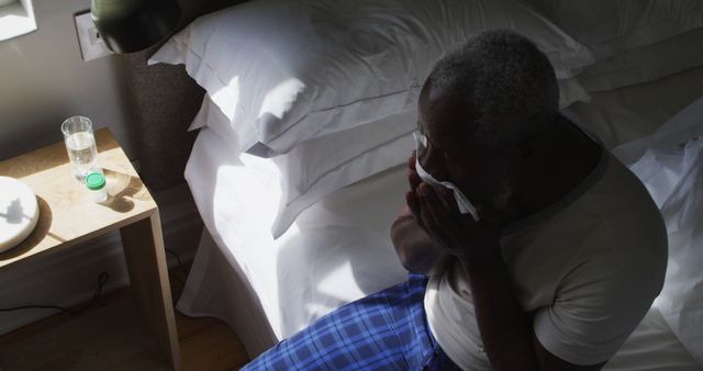 Sick senior african american man couching while sitting on the bed at home - Download Free Stock Photos Pikwizard.com