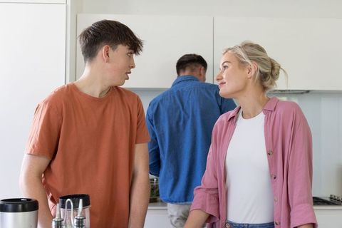 Family chatting in modern kitchen countertop with teen and parents during morning routine
