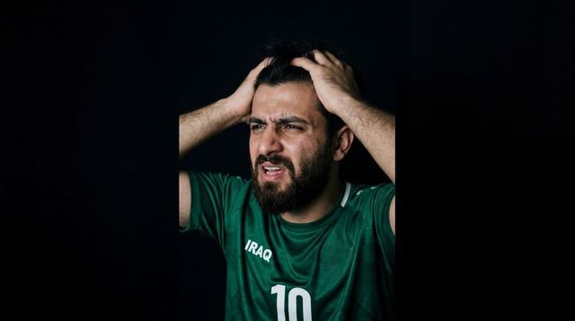 Iraqi football fan gripping hair wearing number 10 jersey expressing agony and frustration