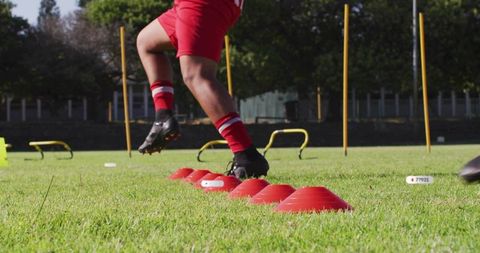 Soccer athlete performing cone agility drill on grass field for speed and conditioning