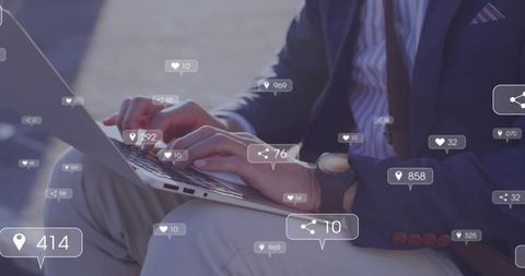Asian businessman typing on laptop with floating social media icons urban outdoor workspace