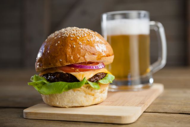 Close-up of burger with glass of beer on chopping board