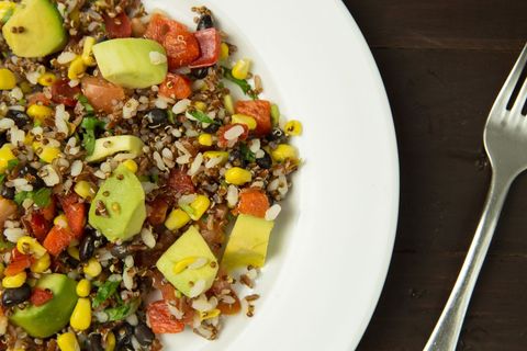 Serving vibrant quinoa and wild rice salad with avocado, black beans, corn and red pepper