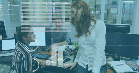Woman leaning and engaging colleagues around analytics dashboard in open-plan office