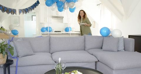 Woman decorating living room with blue and white balloons for a birthday party