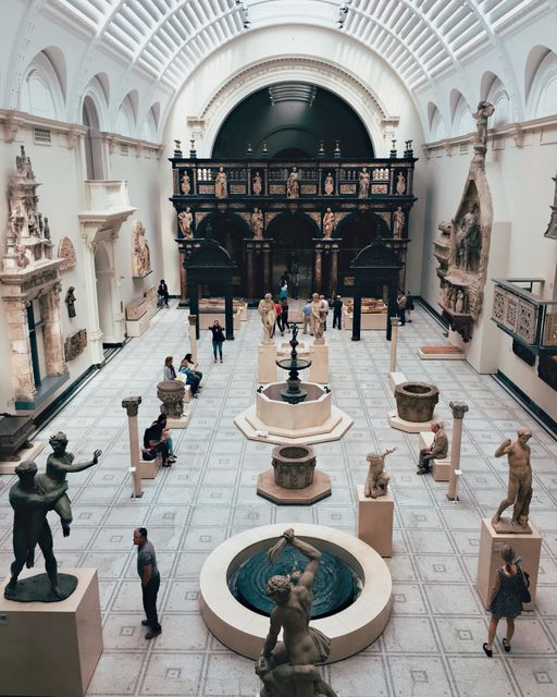 Visitors appreciating various statues in a spacious museum hall under a grand, vaulted ceiling. Useful for topics related to art, history, culture, tourism, and education.