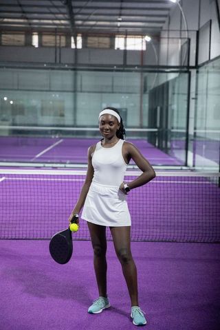 Confident african american padel player wearing white dress on vibrant purple indoor court