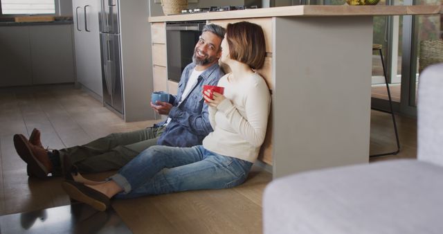 Happy diverse couple sitting in kitchen drinking coffee and talking - Download Free Stock Photos Pikwizard.com