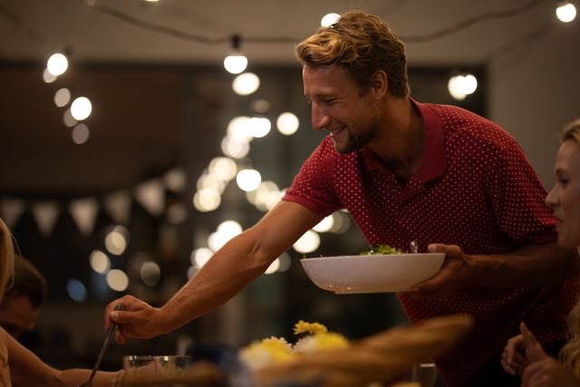 Smiling Man Serving Food to Family at Home Dinner Gathering - Download Free Stock Images Pikwizard.com