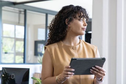 African american professional woman holding tablet and looking out in modern office