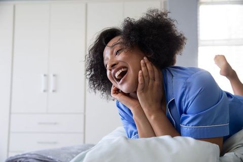 Joyful Middle-Aged Woman in Blue Pajamas Relaxing on Bed