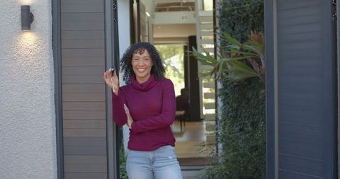 Woman Holding Keys at Modern Home Entrance with Greenery