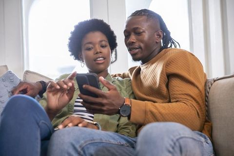 Couple Sharing Moments Through Smartphone on Comforting Sofa