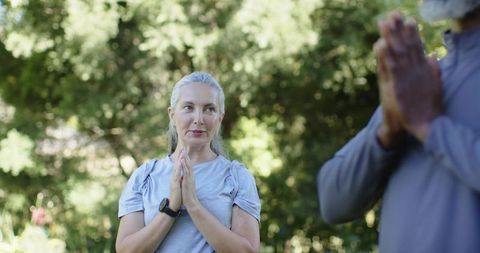 Mature adults practicing mindful yoga and meditation outdoors, wearing smartwatches at sunrise