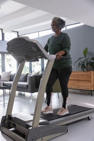 Senior woman exercising on home treadmill in modern living room